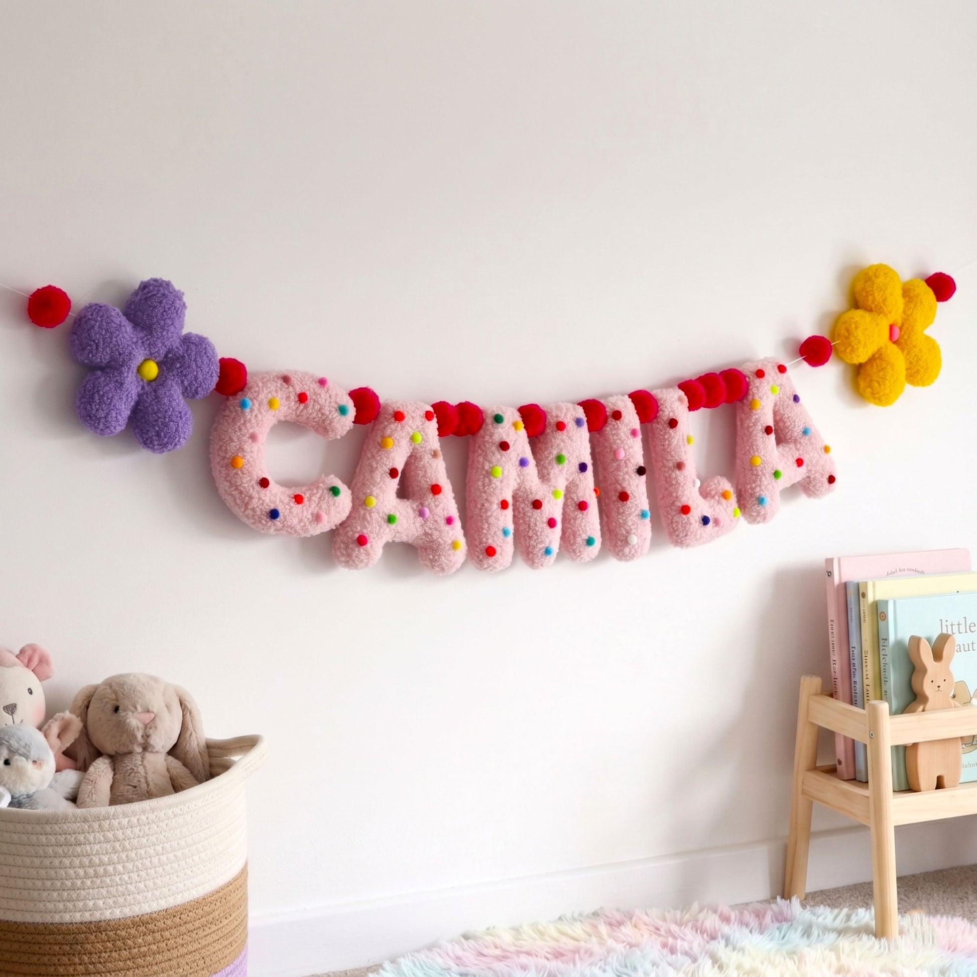 Children's room with a decorative name banner, stuffed animals, and a bookshelf.
