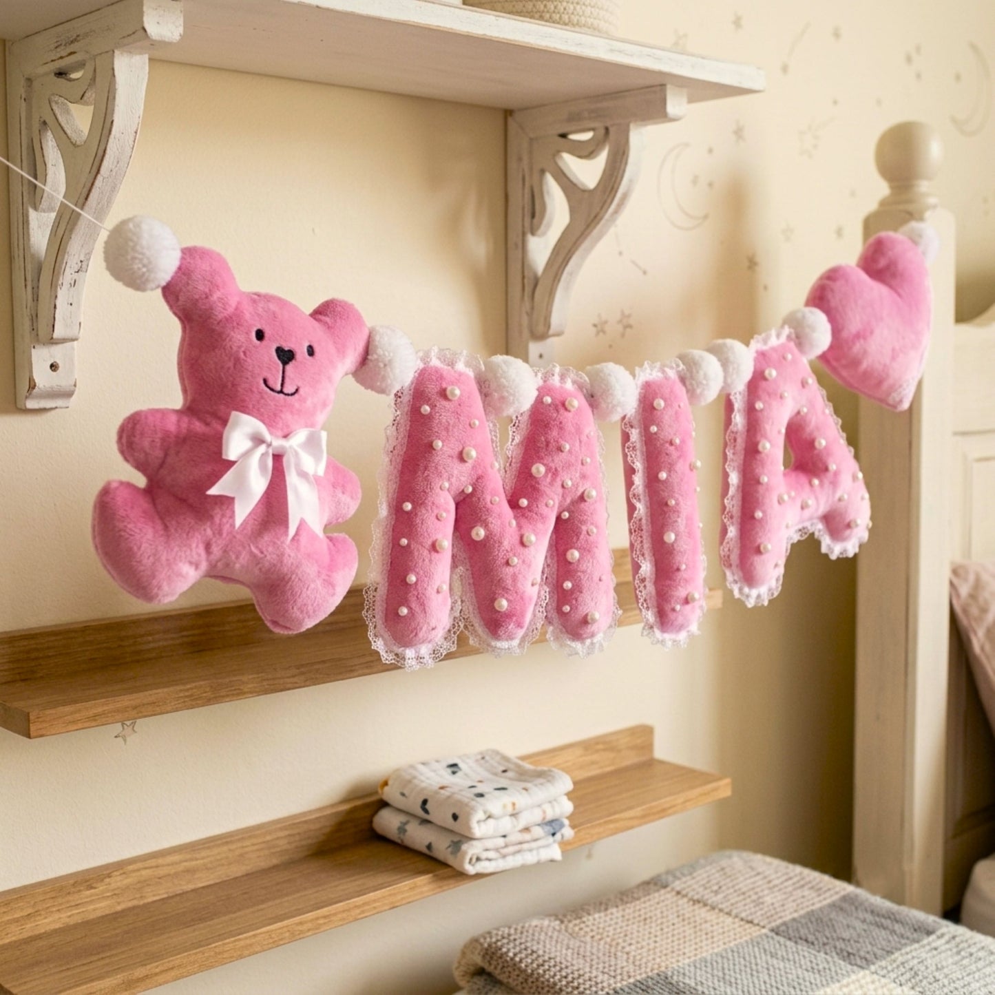 Close-up of pearl-embellished plush letter A beside pink plush heart with lace edge