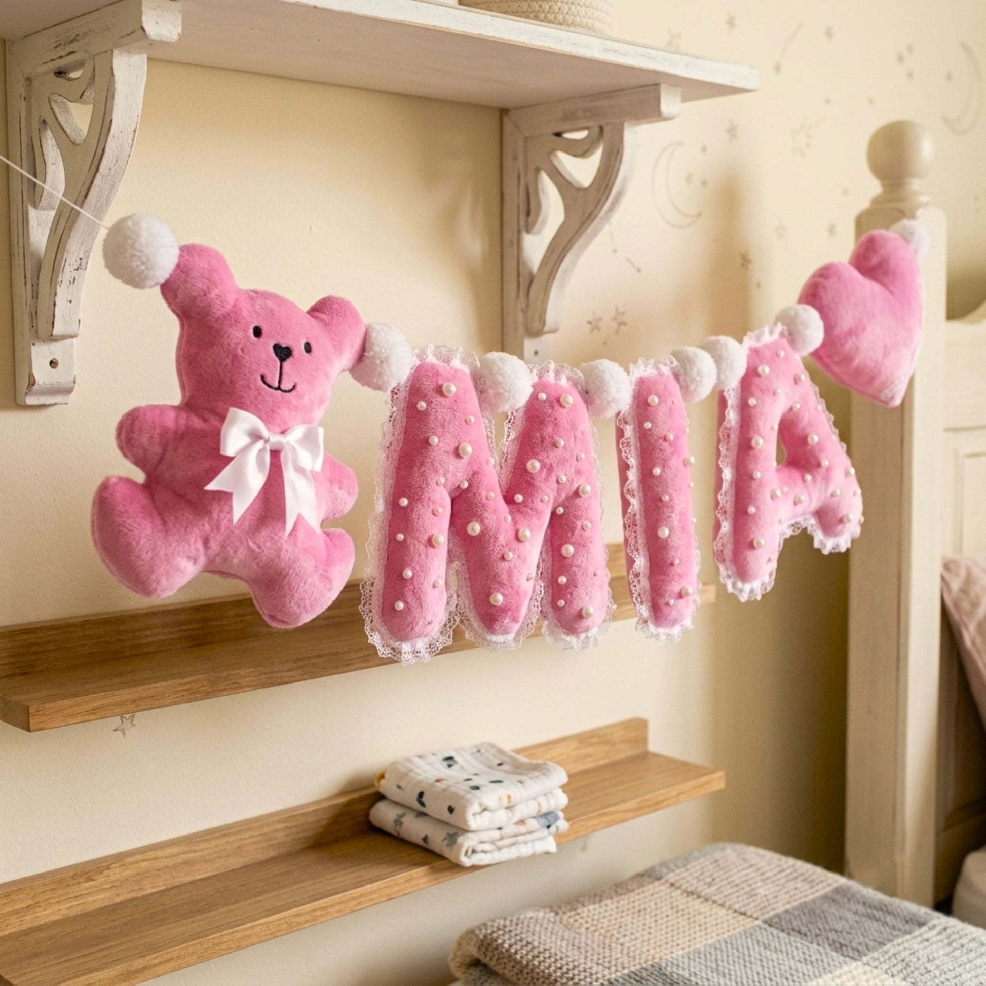 Close-up of pearl-embellished plush letter A beside pink plush heart with lace edge