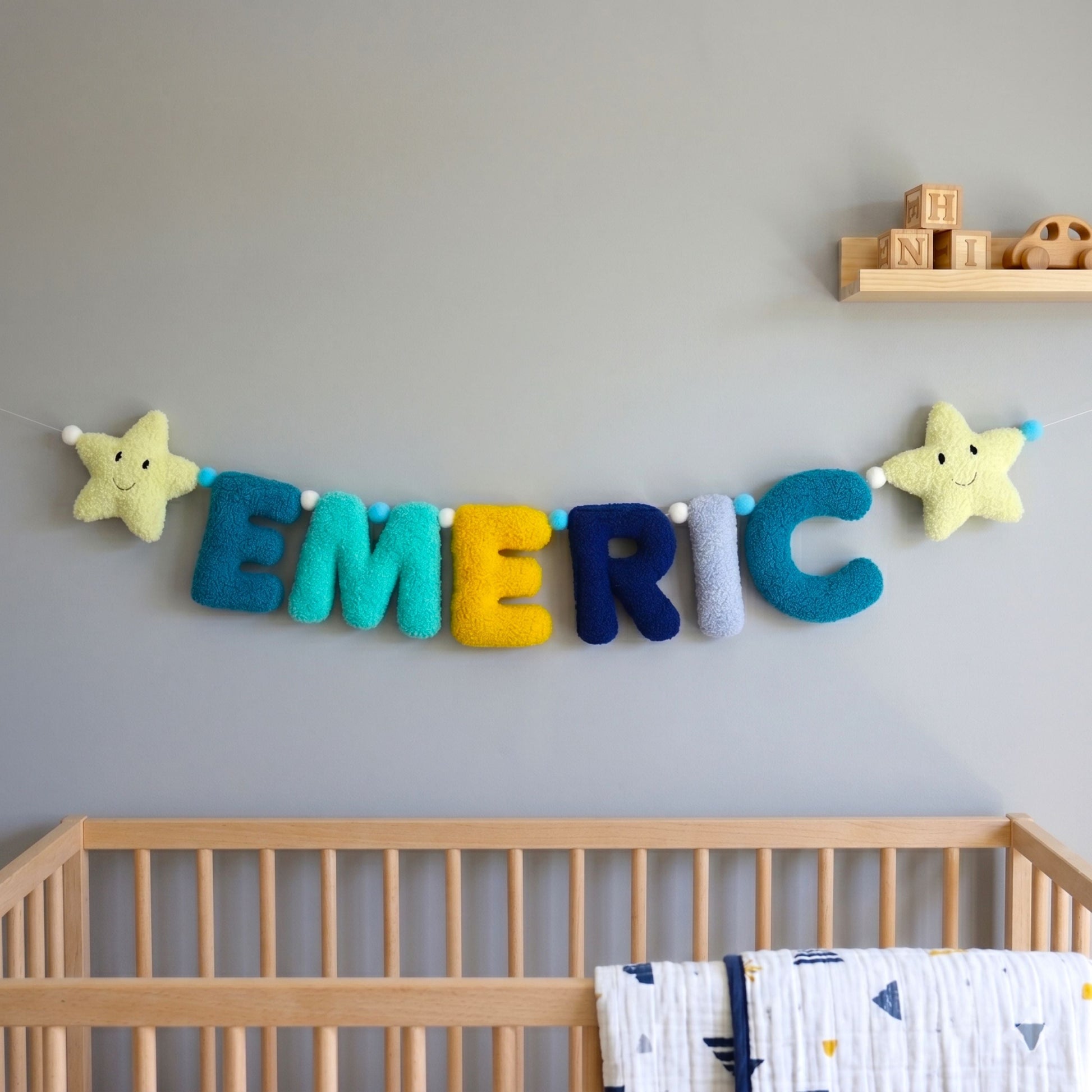 Colorful name banner above a wooden crib in a nursery.