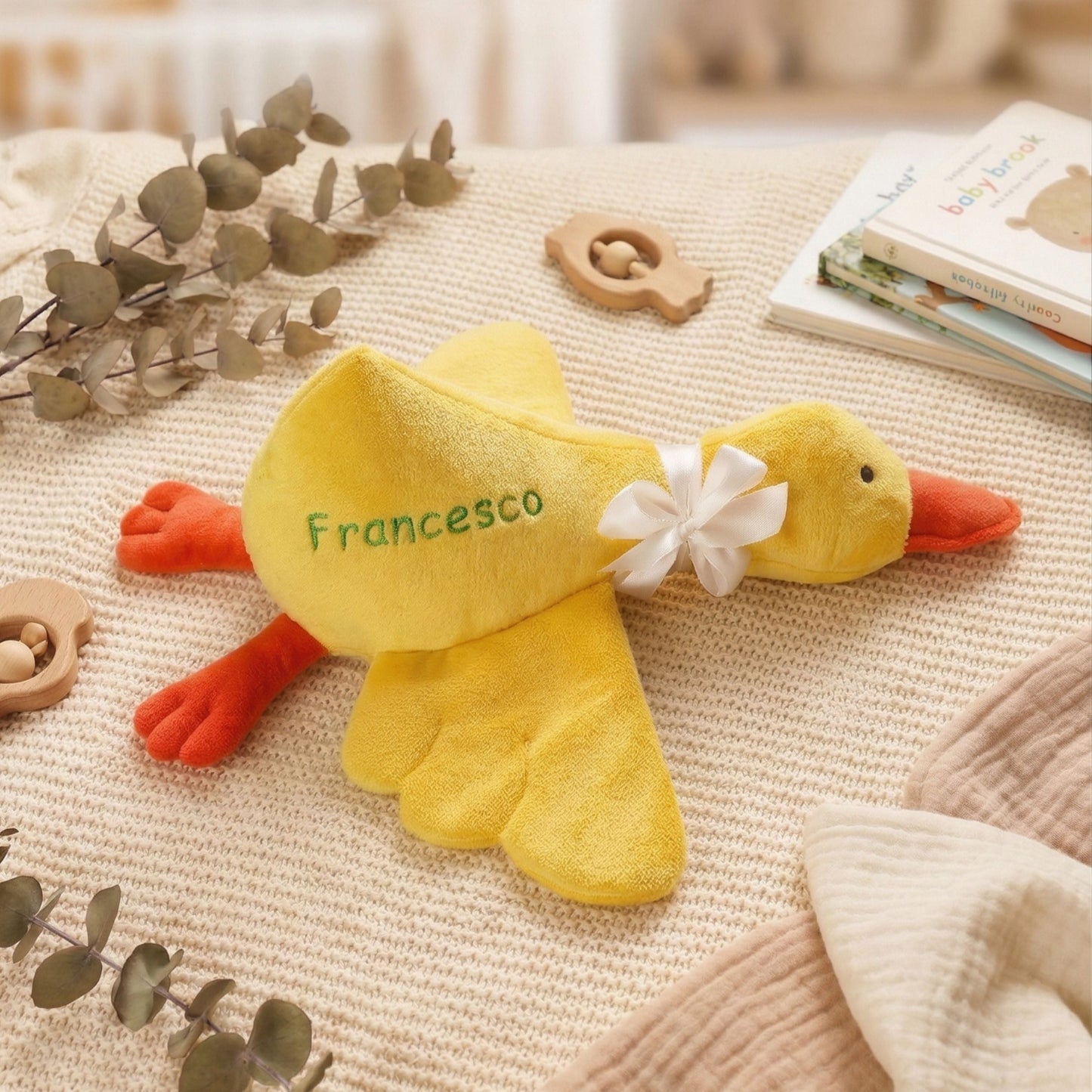 Yellow plush duck toy with 'Francesco' on a textured surface with decorative elements.
