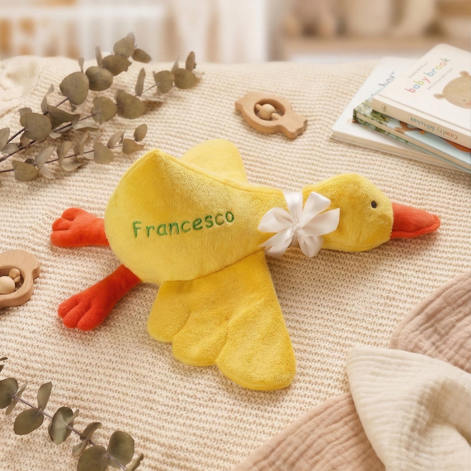 Yellow plush duck toy with 'Francesco' on a textured surface with decorative elements.