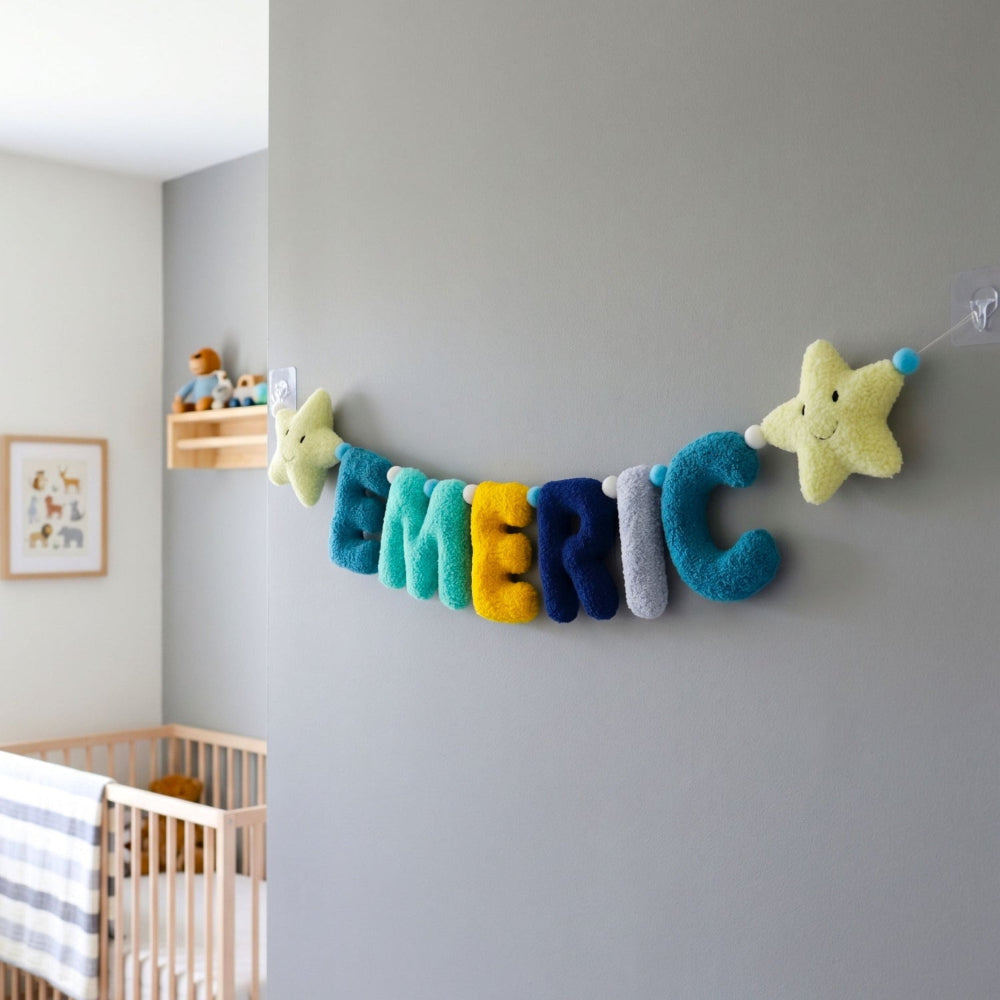 Colorful name banner with stars hanging on a gray wall in a nursery.
