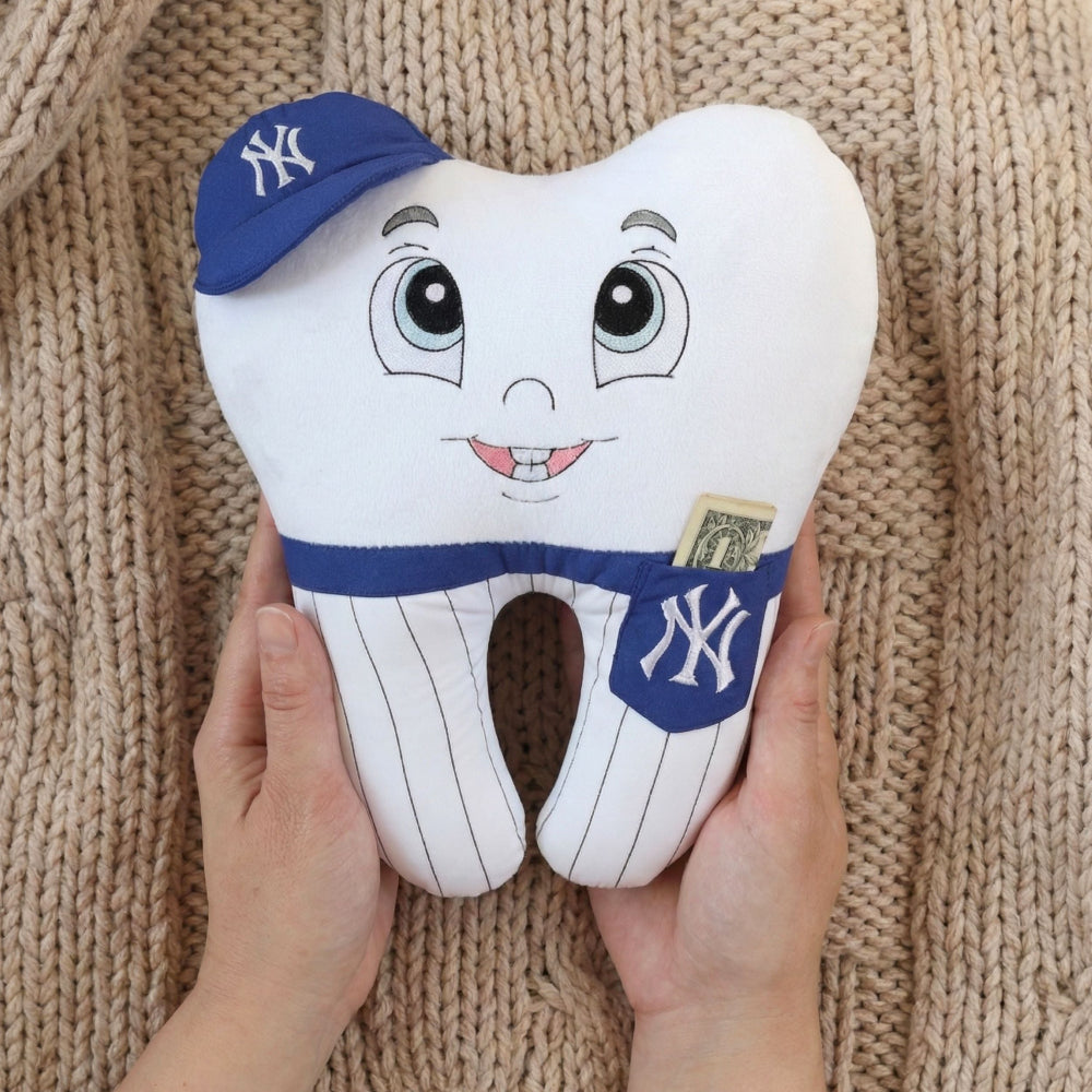 Toy tooth with a New York Yankees cap held against a knitted beige background