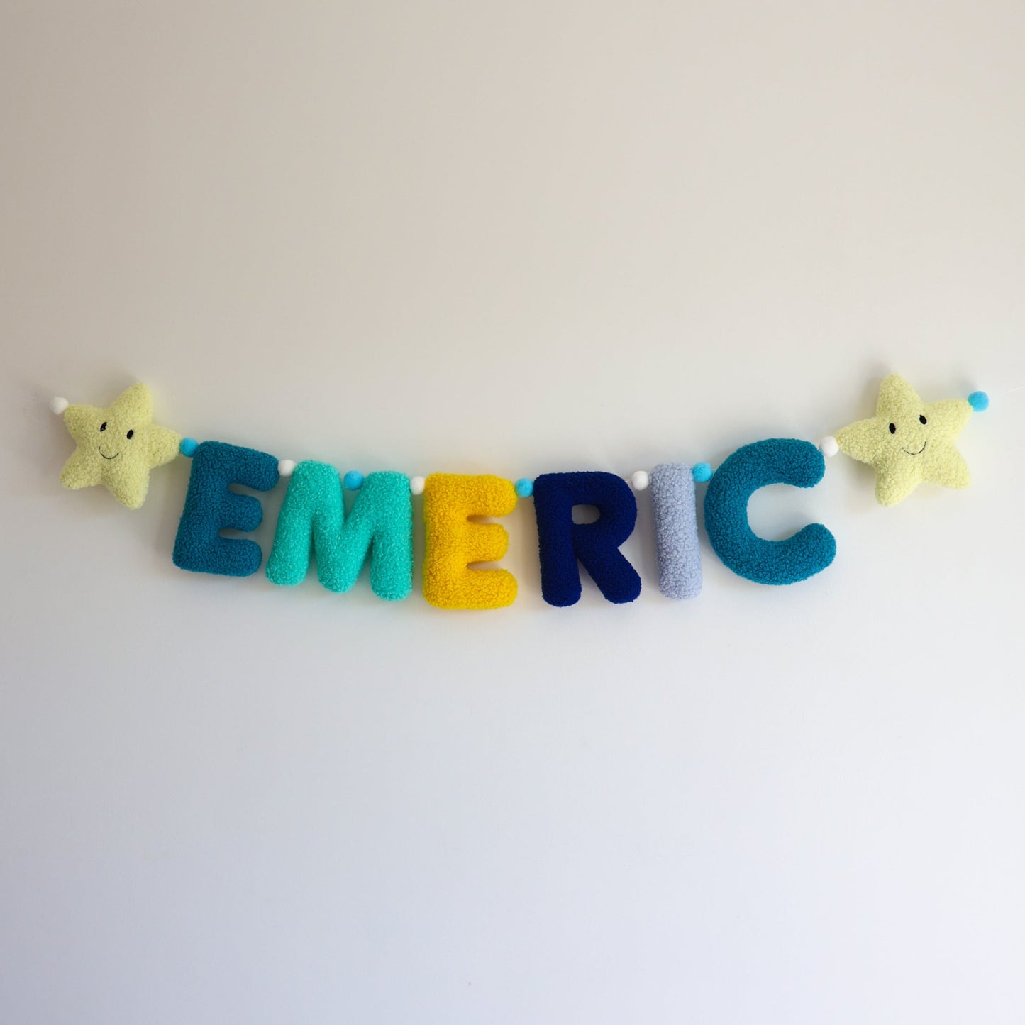 Colorful felt name garland with star-shaped ends on a white background