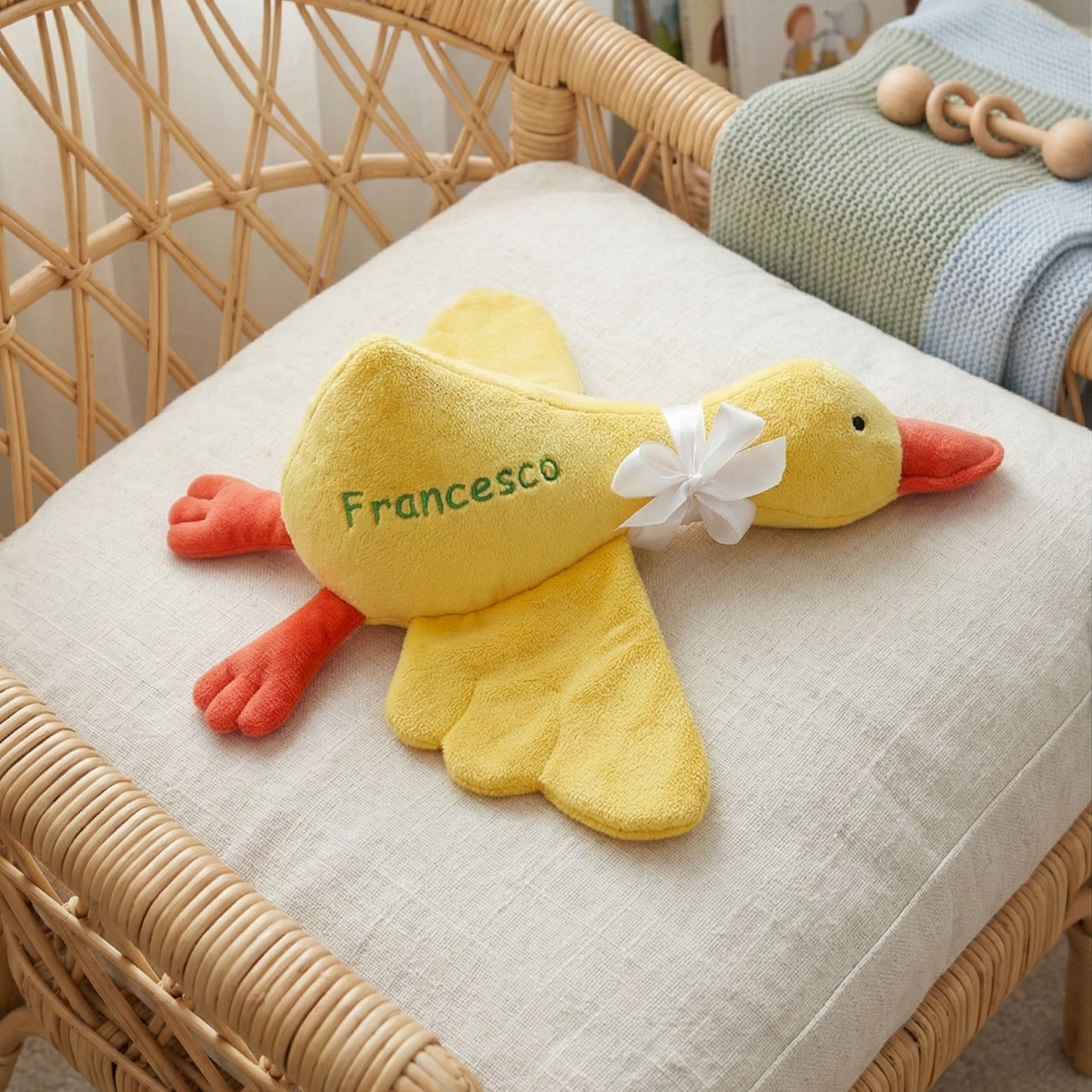 Yellow plush duck toy with 'Francesco' on a cushioned chair