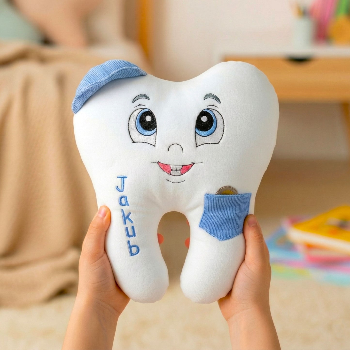 Plush tooth-shaped toy with a face and blue accents, held by hands in a casual setting.