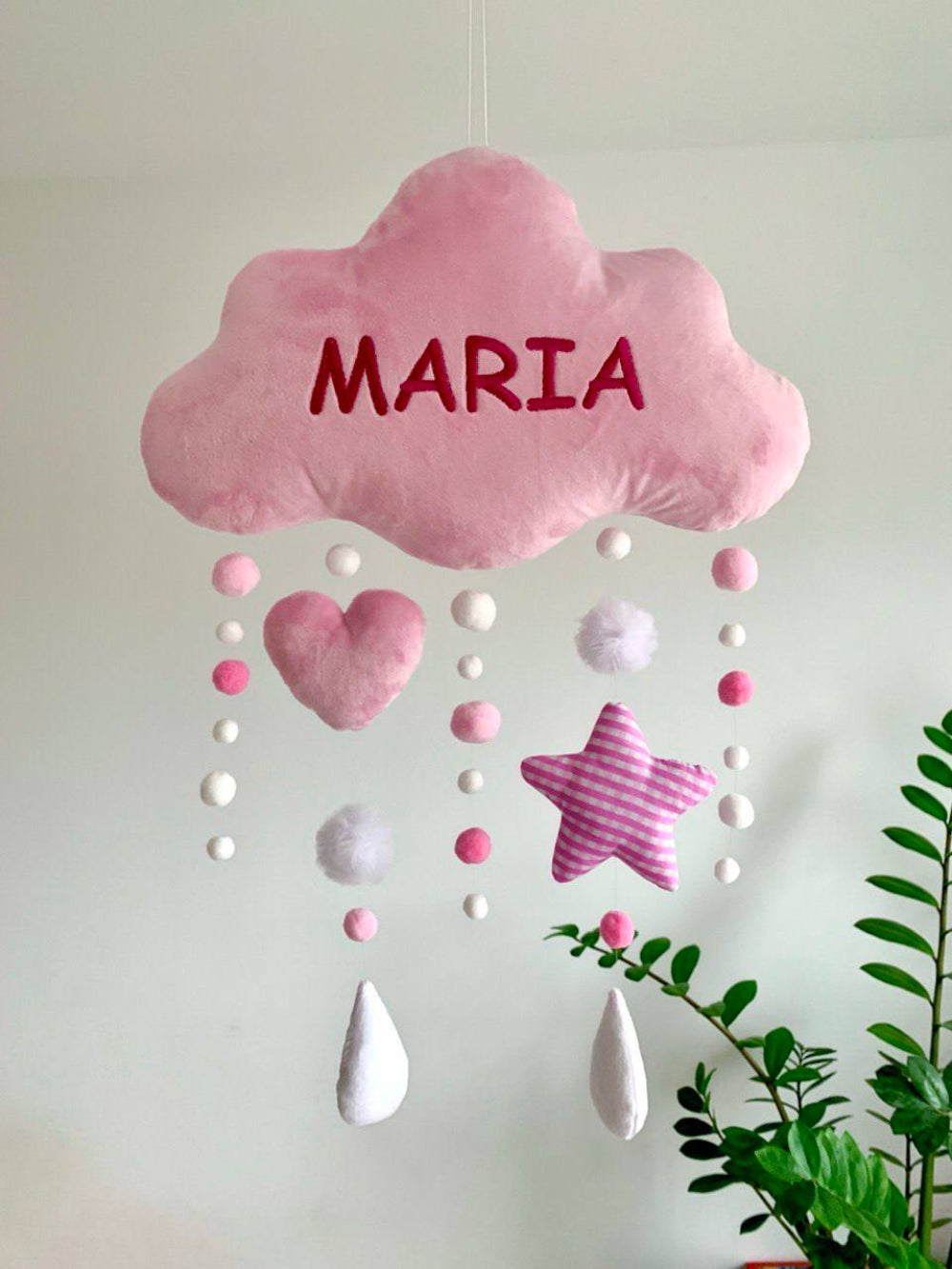 Pink cloud-shaped mobile with  decorative elements on a white background