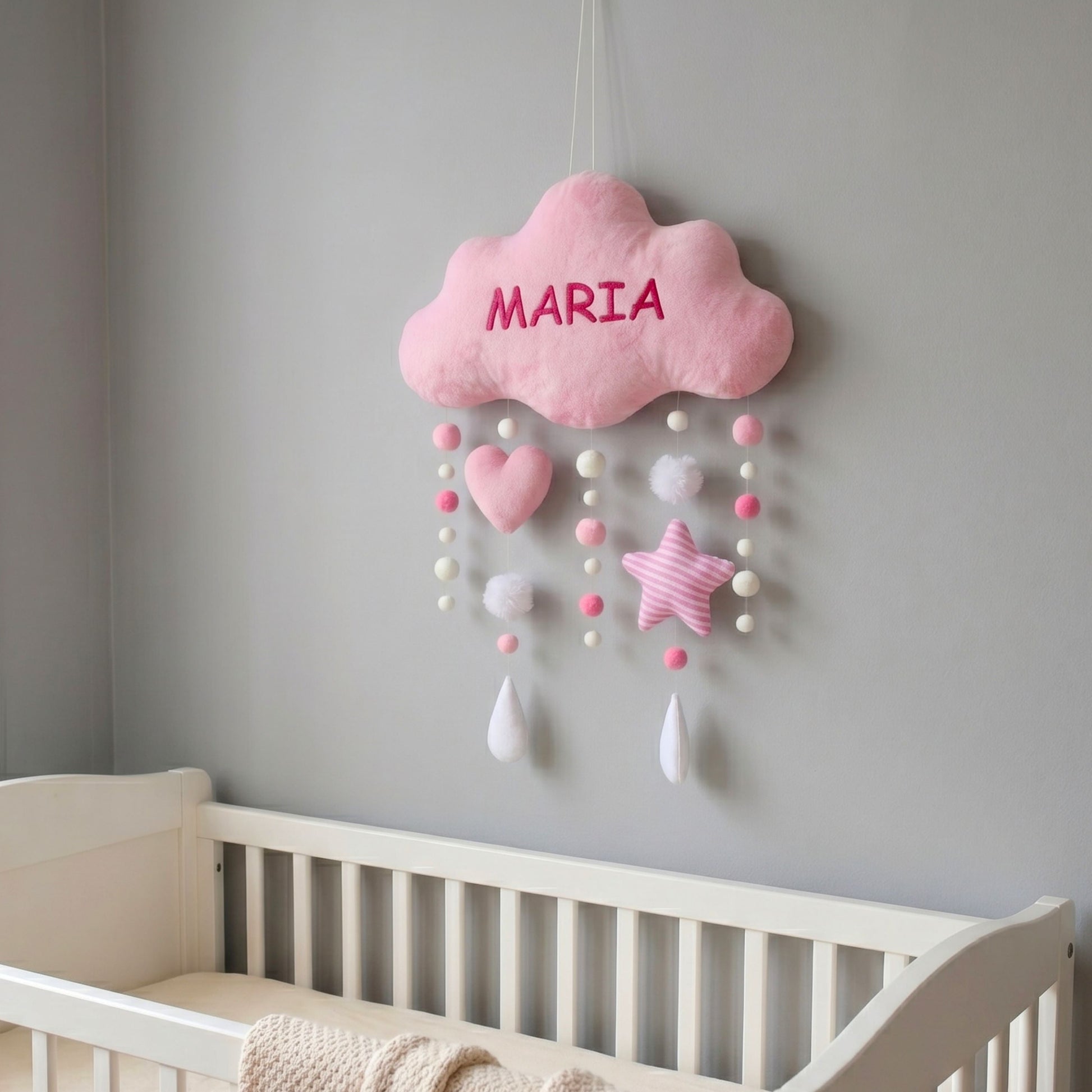 Pink cloud-shaped decoration on a gray wall above a crib.