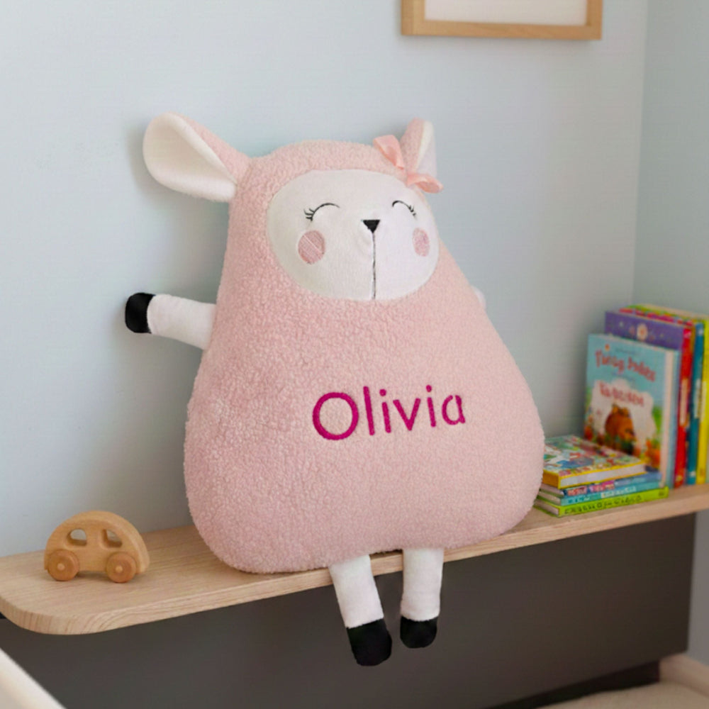 Pink lamb plush toy with 'Olivia' on a shelf in a child's room