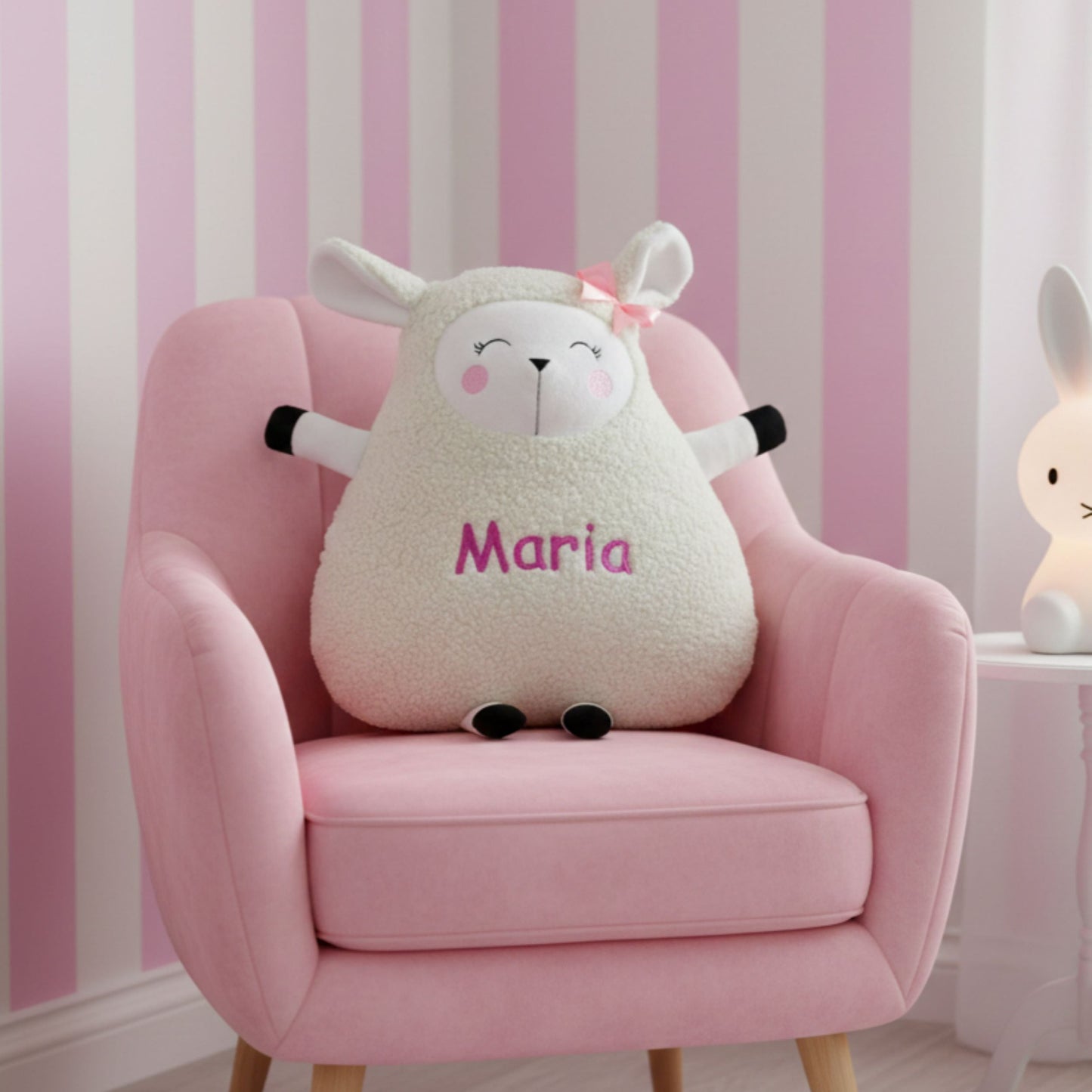 Plush sheep toy named 'Maria' on a pink chair with striped wallpaper in the background