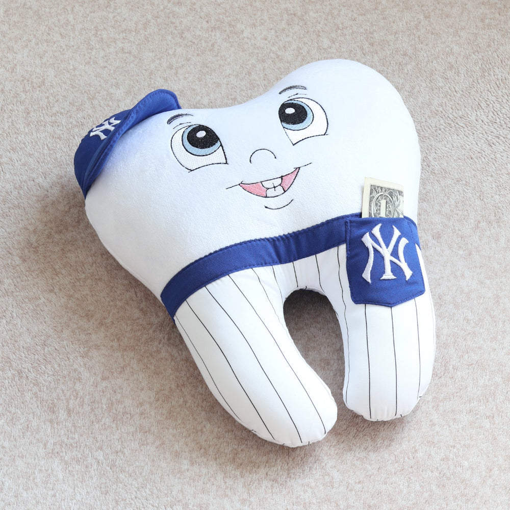 Plush tooth-shaped pillow with cartoon face and New York Yankees logo on a beige surface