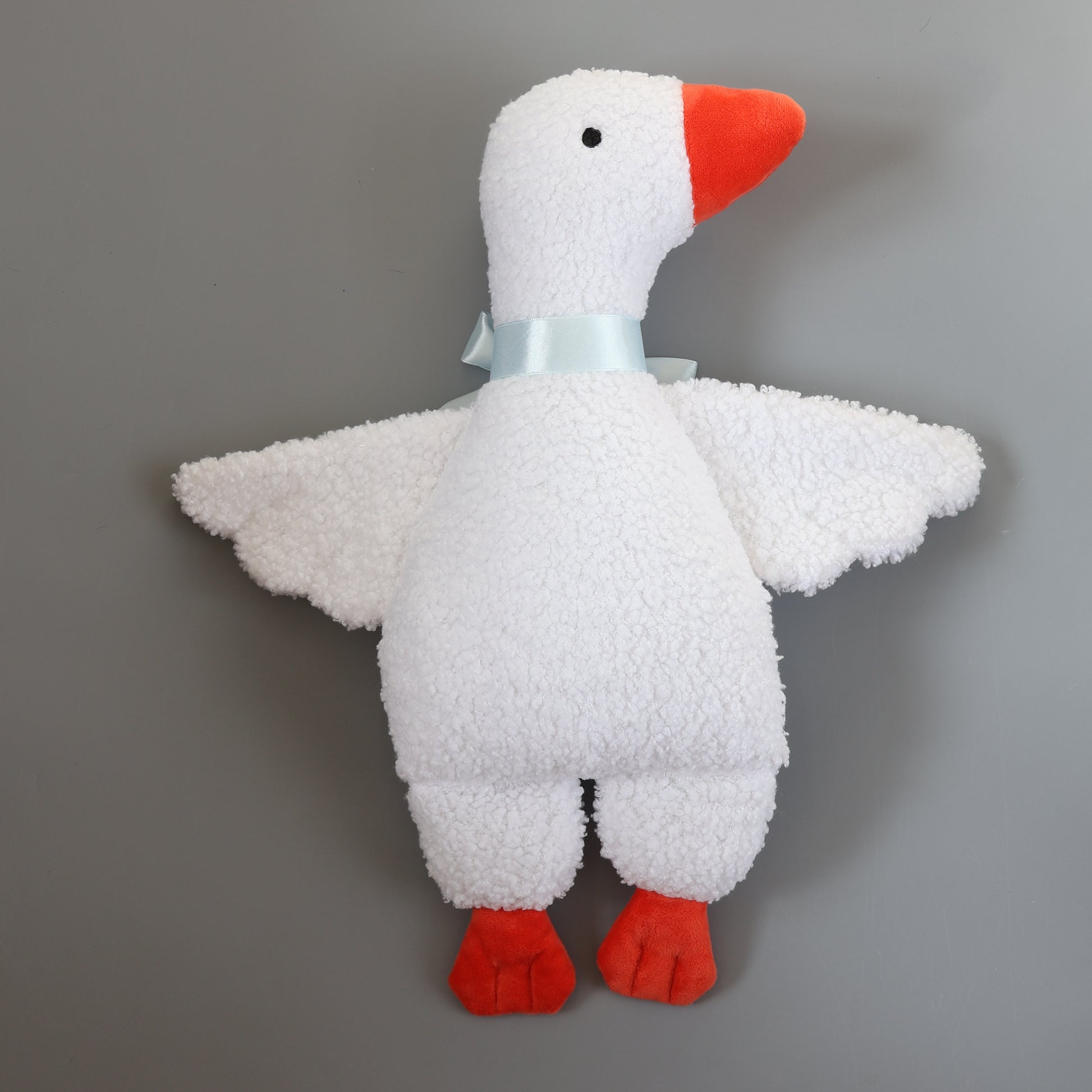 White plush toy goose with red feet and beak on a gray background