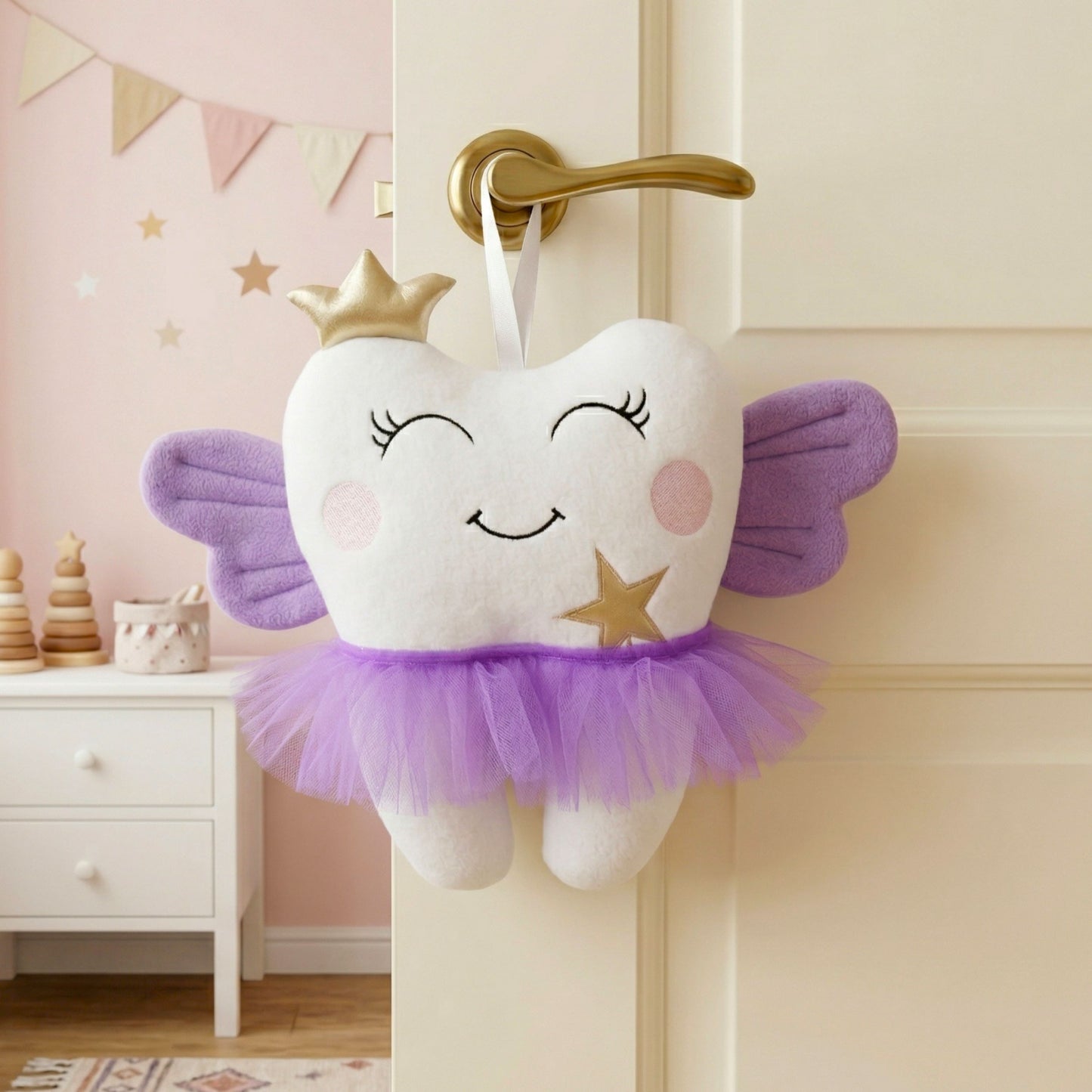 Plush tooth fairy pillow with wings and a crown hanging on a door in a child's room.