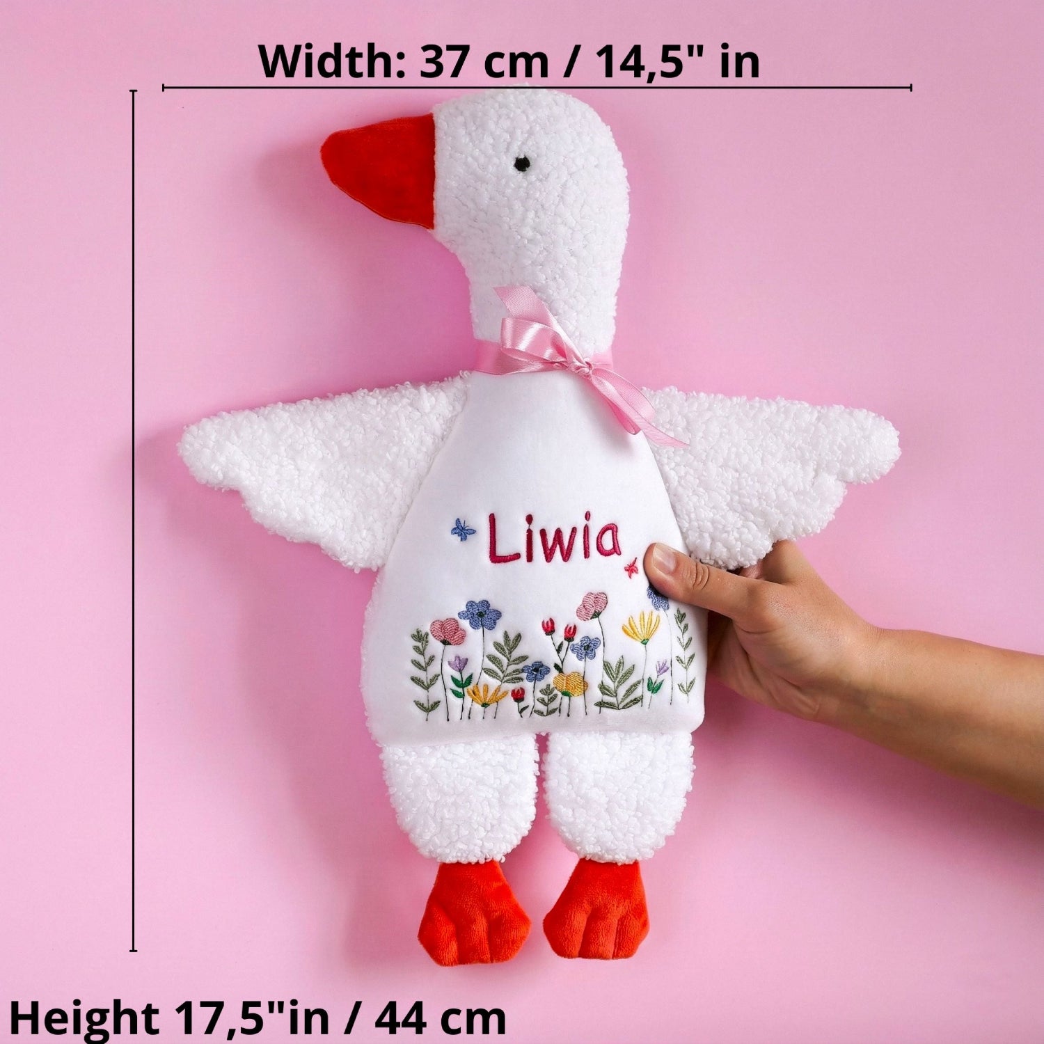 Plush goose toy with 'Liwia' on a pink background, held by a hand.