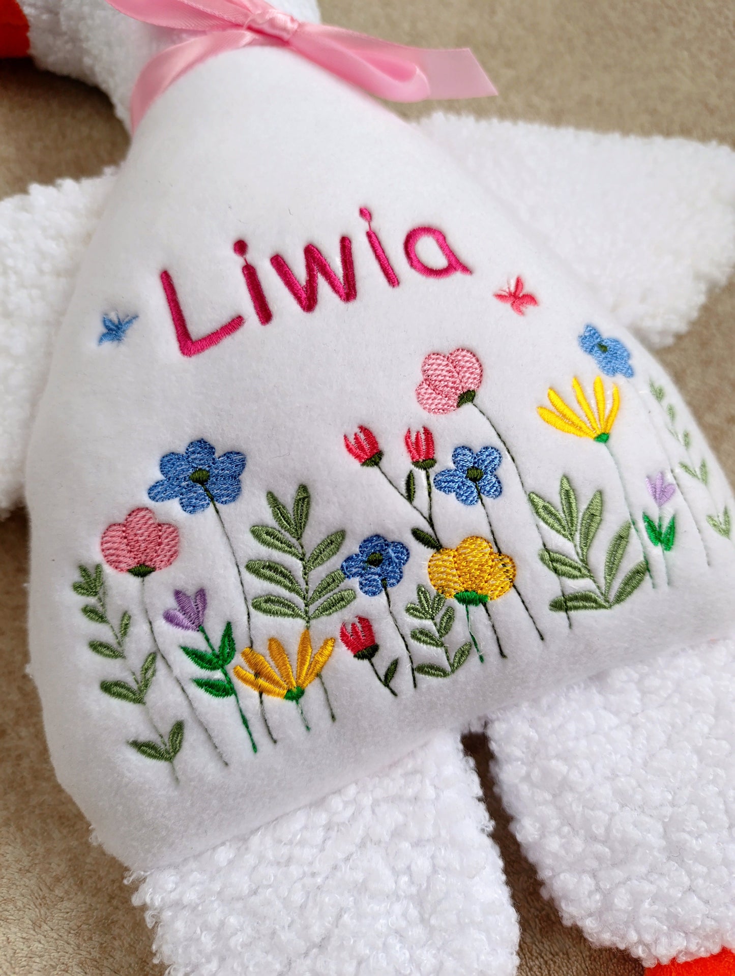 White teddy bear goose with embroidered flowers and the name 'Liwia' on a beige background
