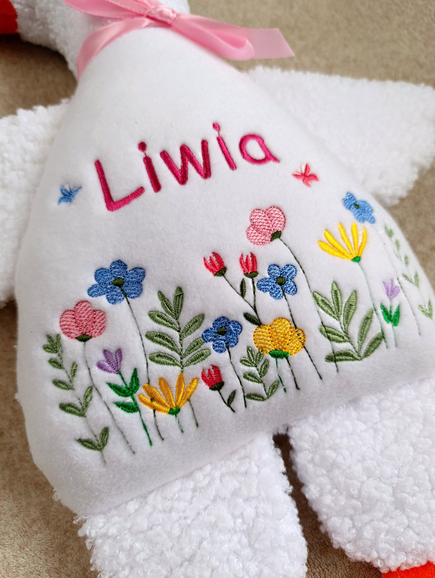 White teddy bear goose with embroidered flowers and the name 'Liwia' on a beige background