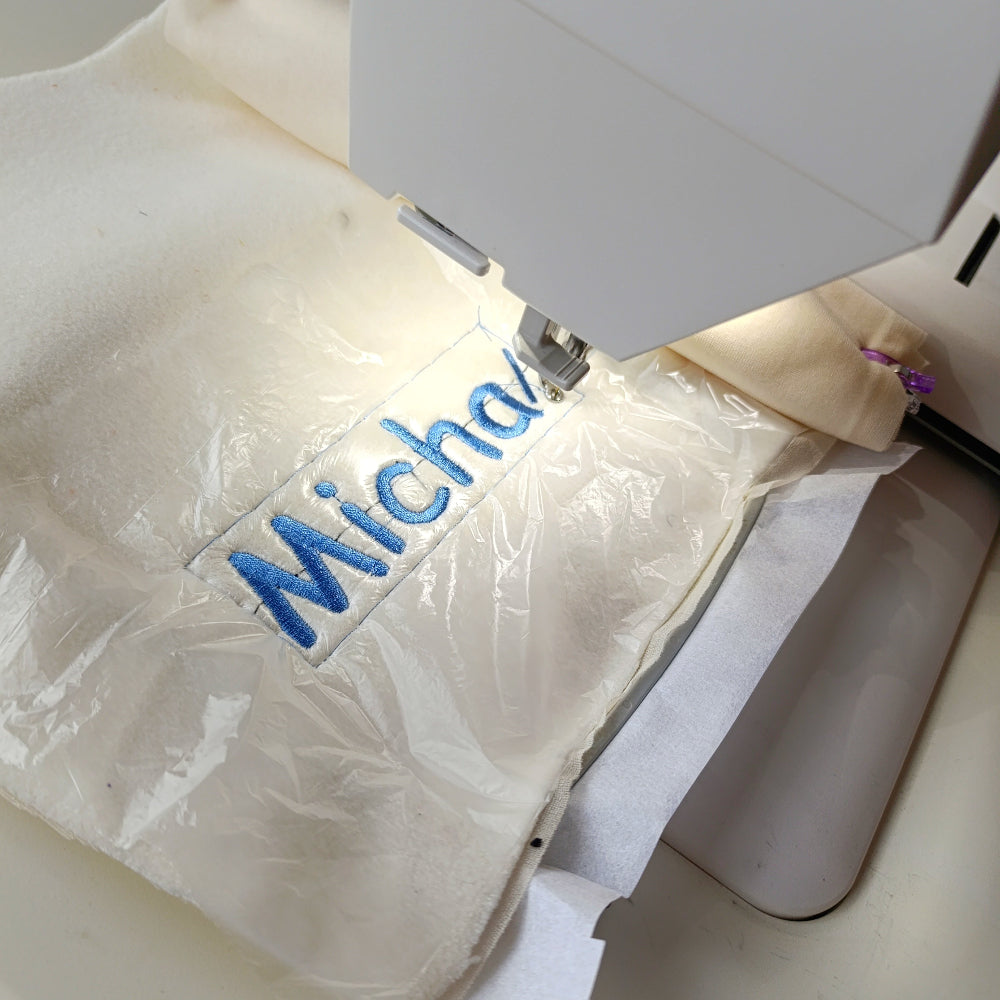Sewing machine with a piece of fabric being embroidered with the name 'Michael'.