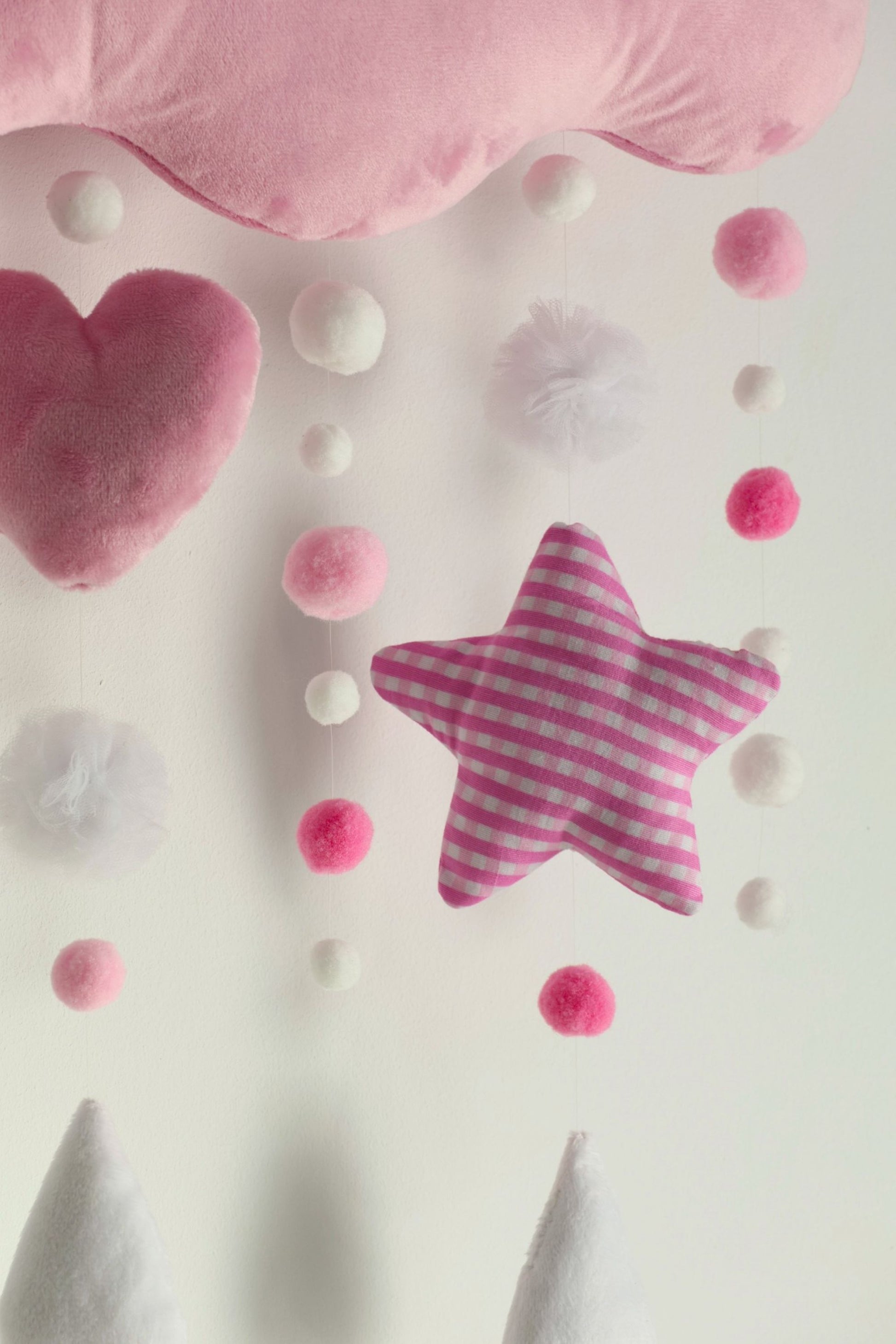Pink star-shaped nursery decor with heart and round ball decorations on a light background