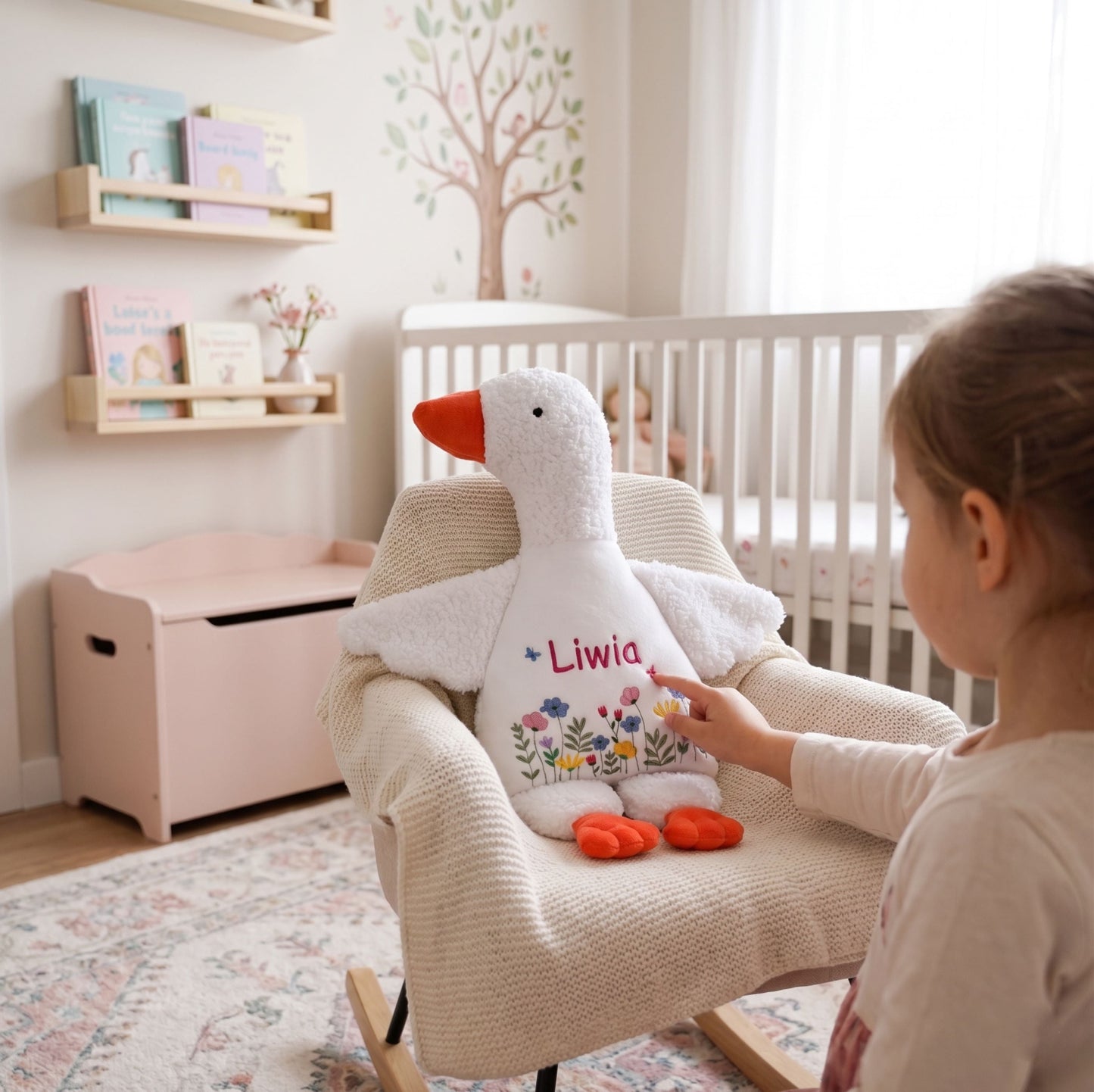 Child holding a personalized stuffed goose toy in a nursery