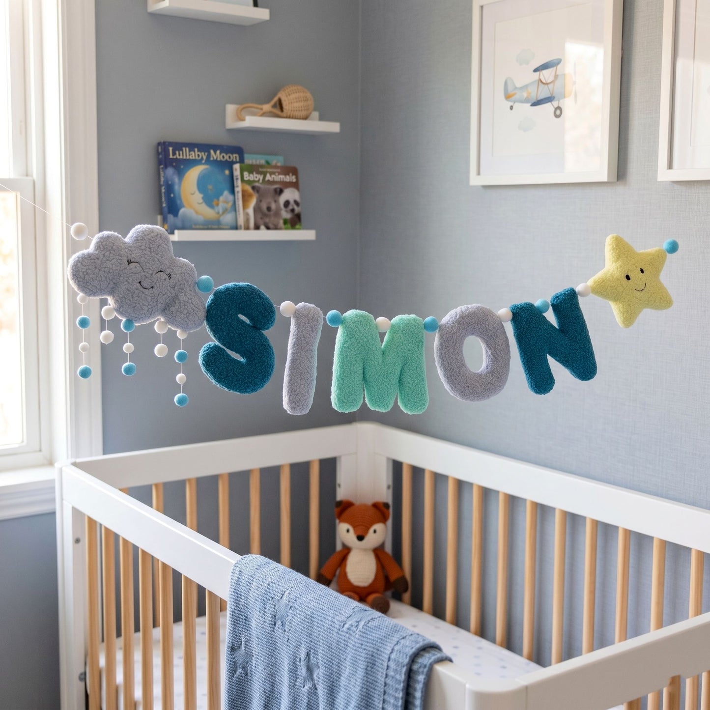 Nursery room with crib, decorative name banner, and books on a shelf.