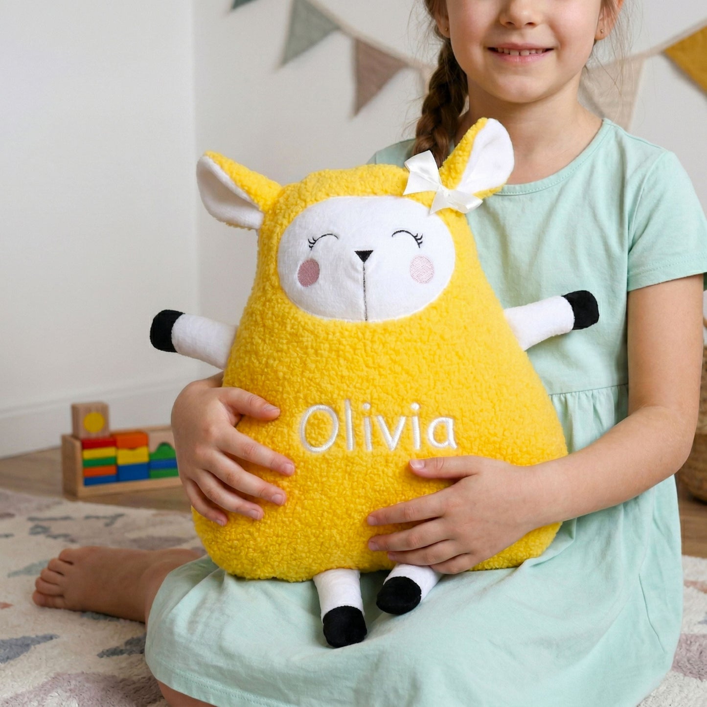 Child holding a yellow plush toy with 'Olivia' on it in a room setting.